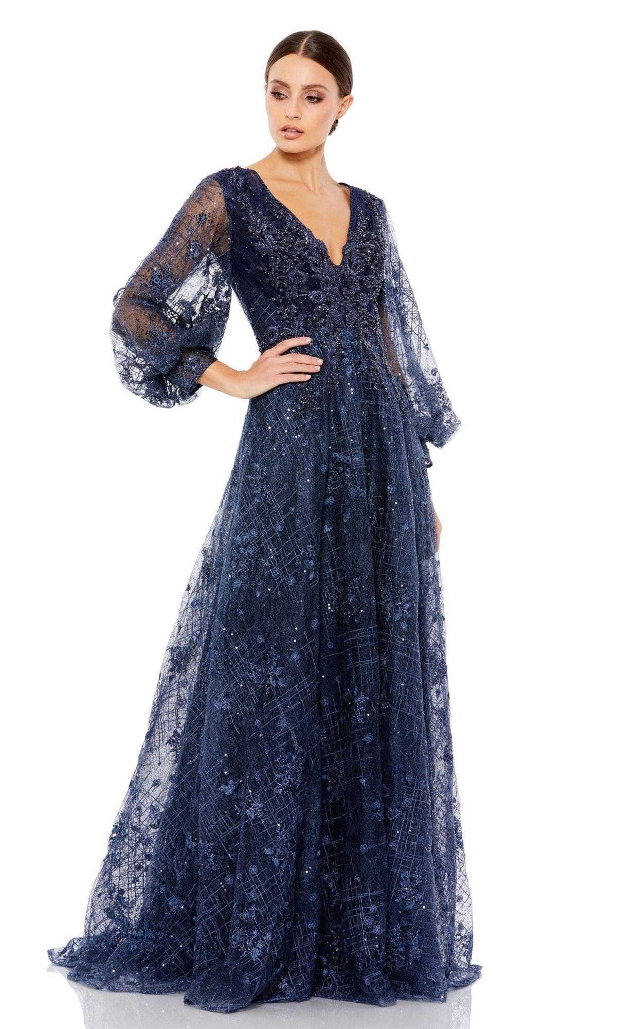 A woman poses elegantly against a white background in the Long Formal Dress 20283 by Mac Duggal, featuring navy blue embroidery, sheer puff sleeves, and floral detailing.